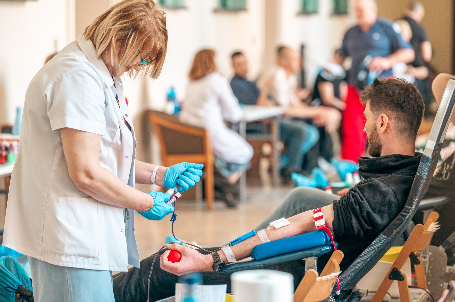 Na zdjęciu kobieta pobierająca krew, w tle czekający ludzie