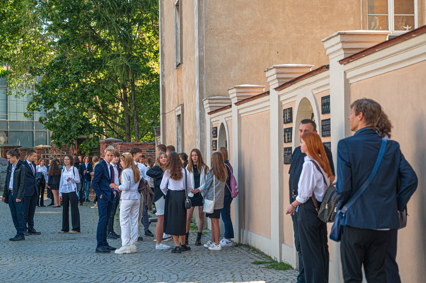 Zdjęcie przedstawia uczniów stojących przed szkołą. - grafika artykułu