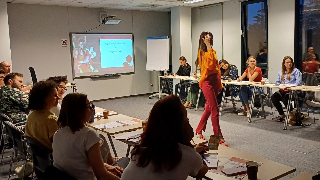 Grafika przedstawiająca zdjęcie ze szkolenia. Na zdjęciu są uczestnicy szkolenia stacjonarnego, którzy siedzą w sali szkoleniowej.