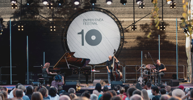 Zdjęcie przedstawia muzyków grających na scenie. W tle widać nazwę festiwalu oraz liczbę 10.