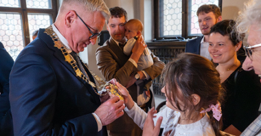 Prezydent Poznania z oficjalnym łańcuchem na szyi, który ogląda mała dziewczynka