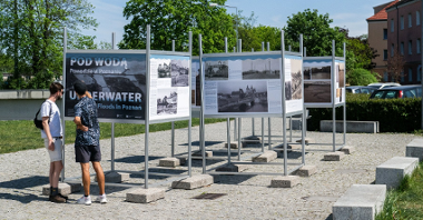 Galeria zdjęć przedstawia ludzi oglądających wystawę "Pod wodą. Powodzie w Poznaniu".