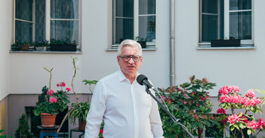 Na zdjęciu prezydent Poznania przed mikrofonem na podwórku
