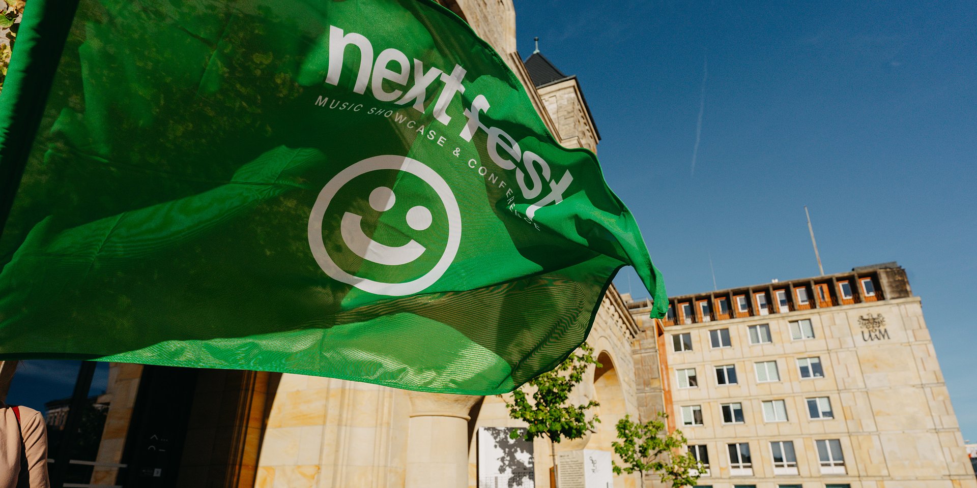 Powiewająca zielona flaga Next Fest przed CK Zamek - grafika artykułu