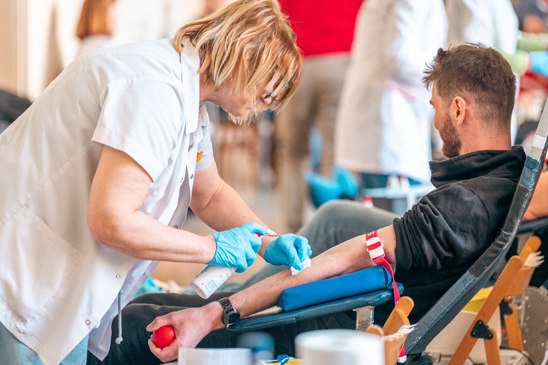 Na zdjęciu pielęgniarka pochylona nad mężczyzną, który za chwilę odda krew - grafika artykułu
