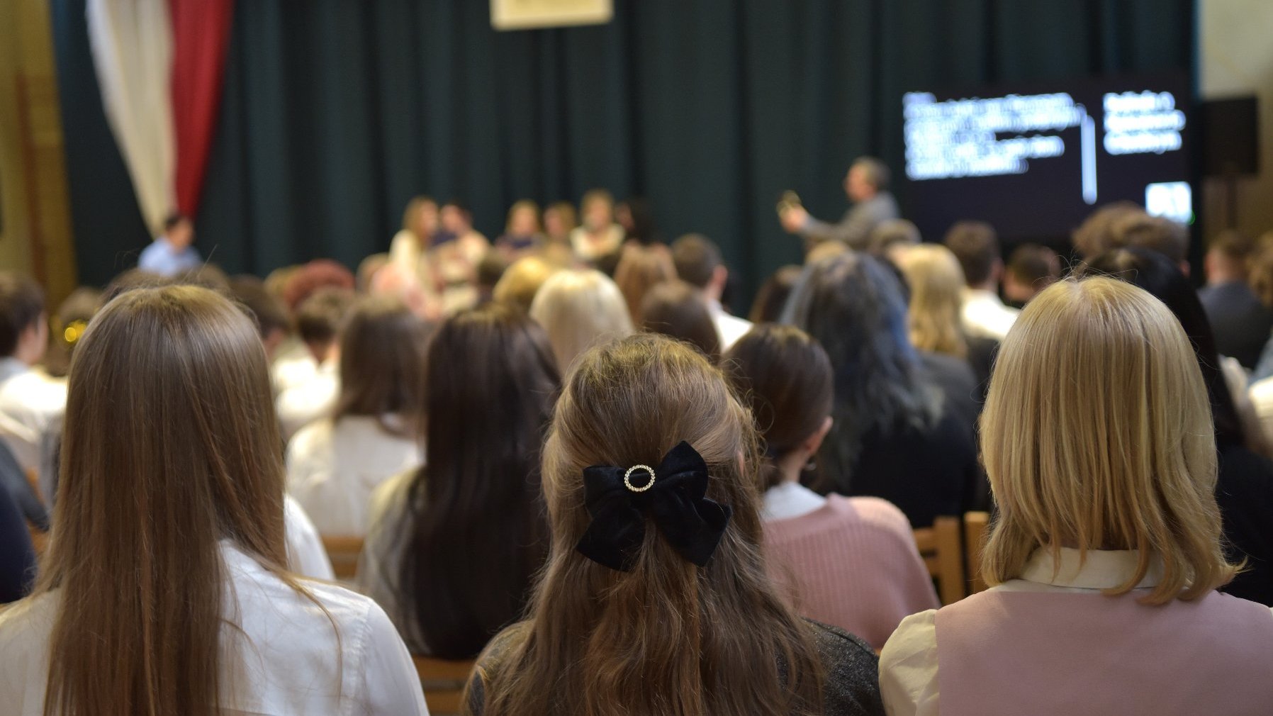 Zdjęcie przedstawia uczniów siedzących na sali gimnastycznej.