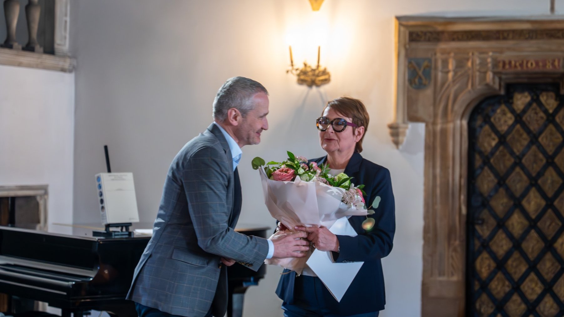 Zdjęcie przedstawia mężczyznę wręczającego kwiaty kobiecie.