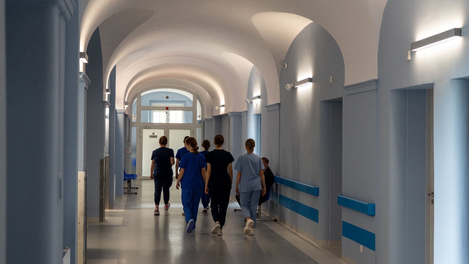 Na zdjęciu szpitalny korytarz, nim idzie personel szpitala