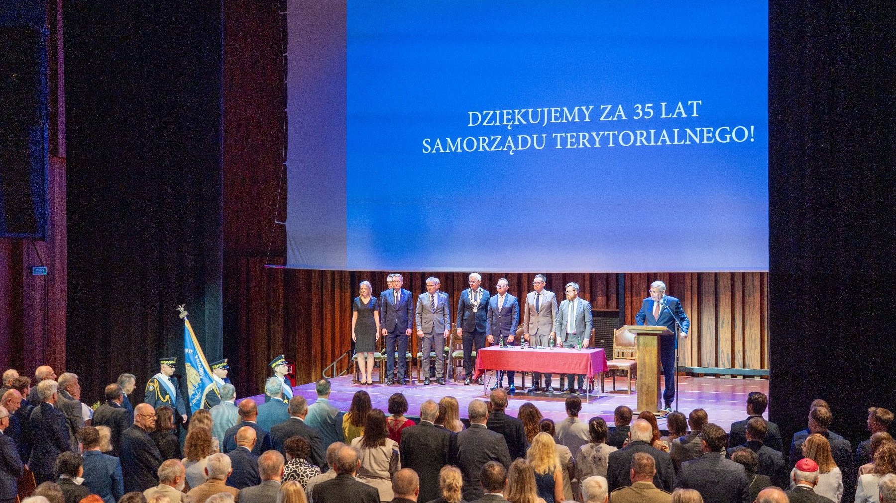 Na zdjęciu grupa ludzi na scenie, w tle napis: dziękujemy za 35 lat samorządu terytorialnego