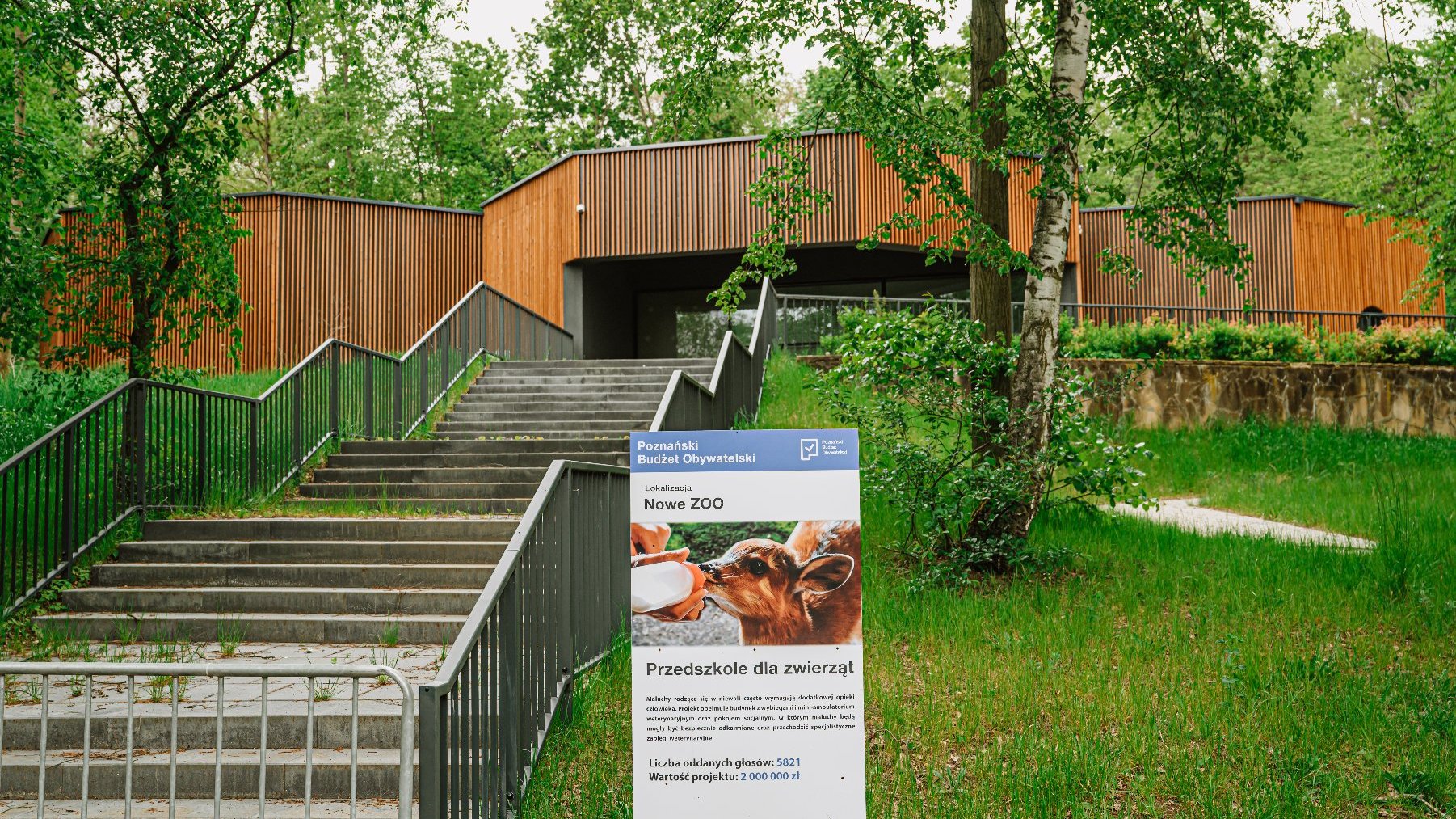 Zdjęcie przedstawia budynek wśród zieleni.