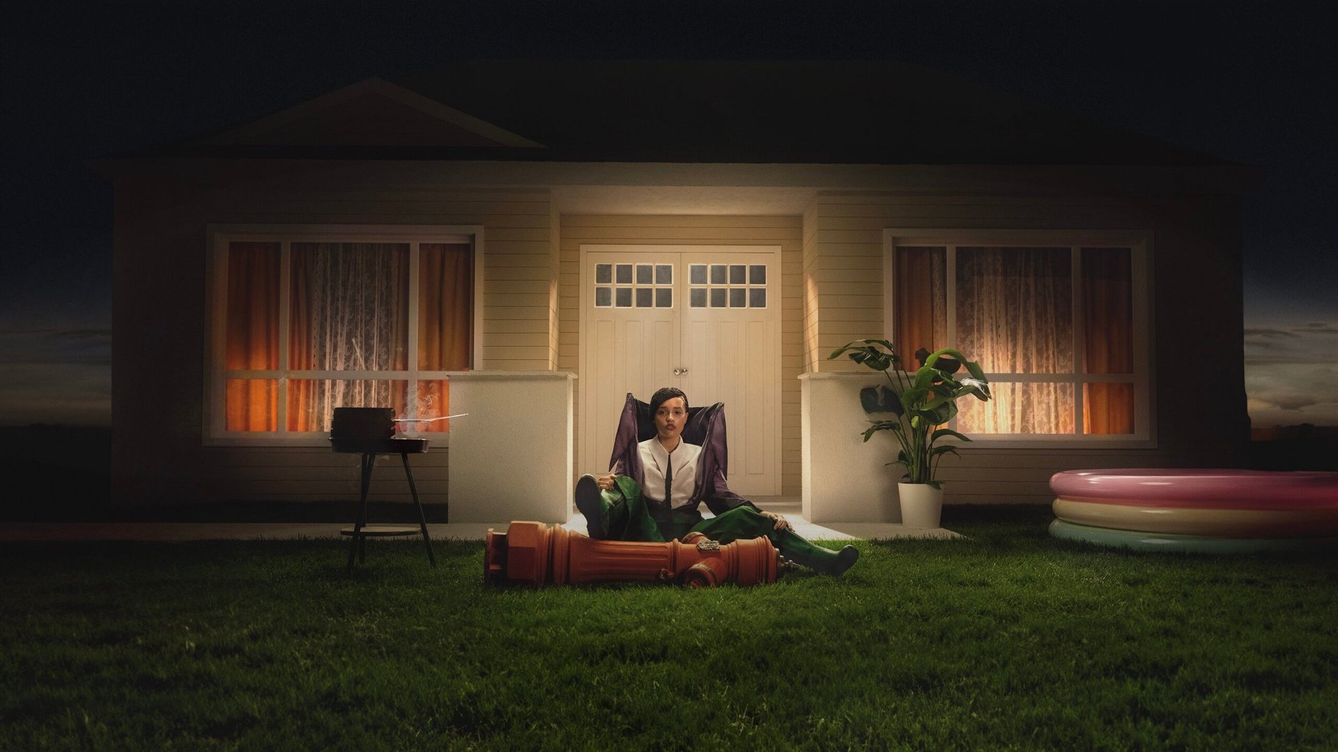 Inscenizowane zdjęcie siedzącej Sary James przed dekoracją przypominającą dom