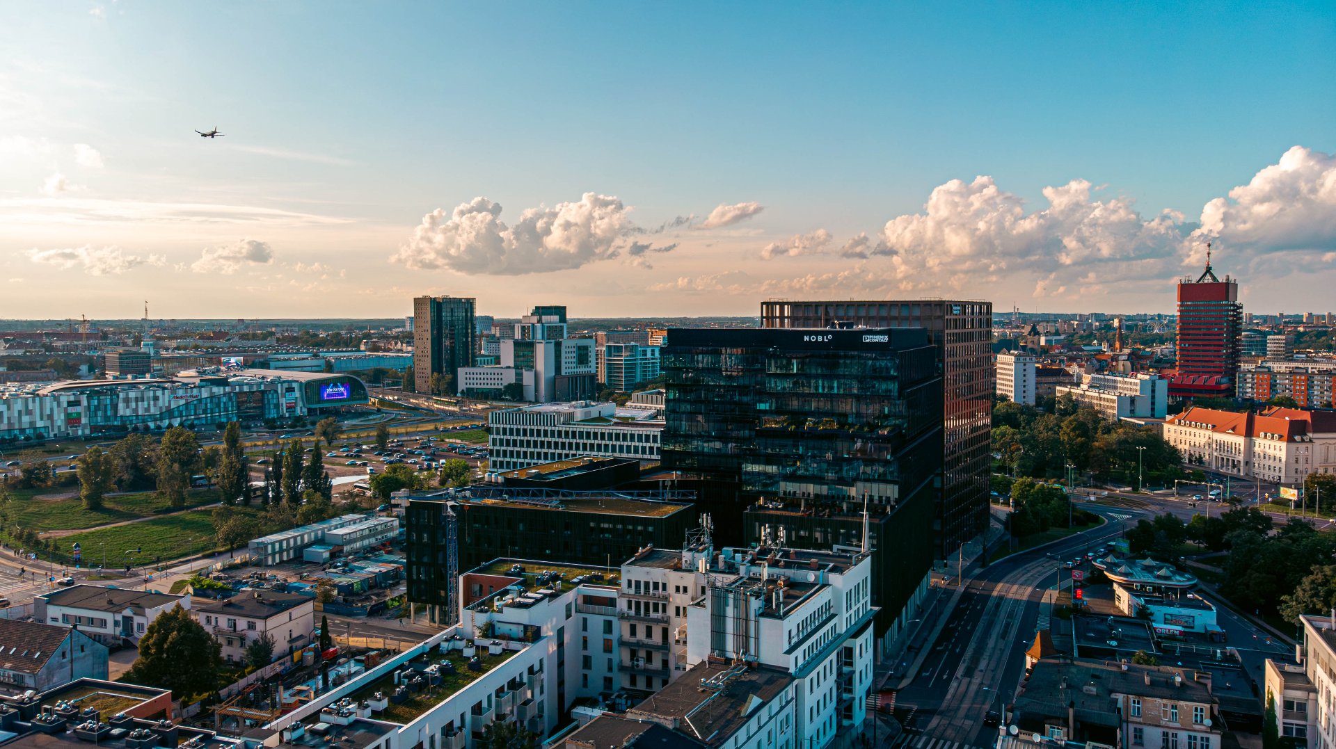 Panorama miasta w słoneczny dzień. W centrum kadru dominuje duży, nowoczesny, czarny budynek biurowy. - grafika artykułu