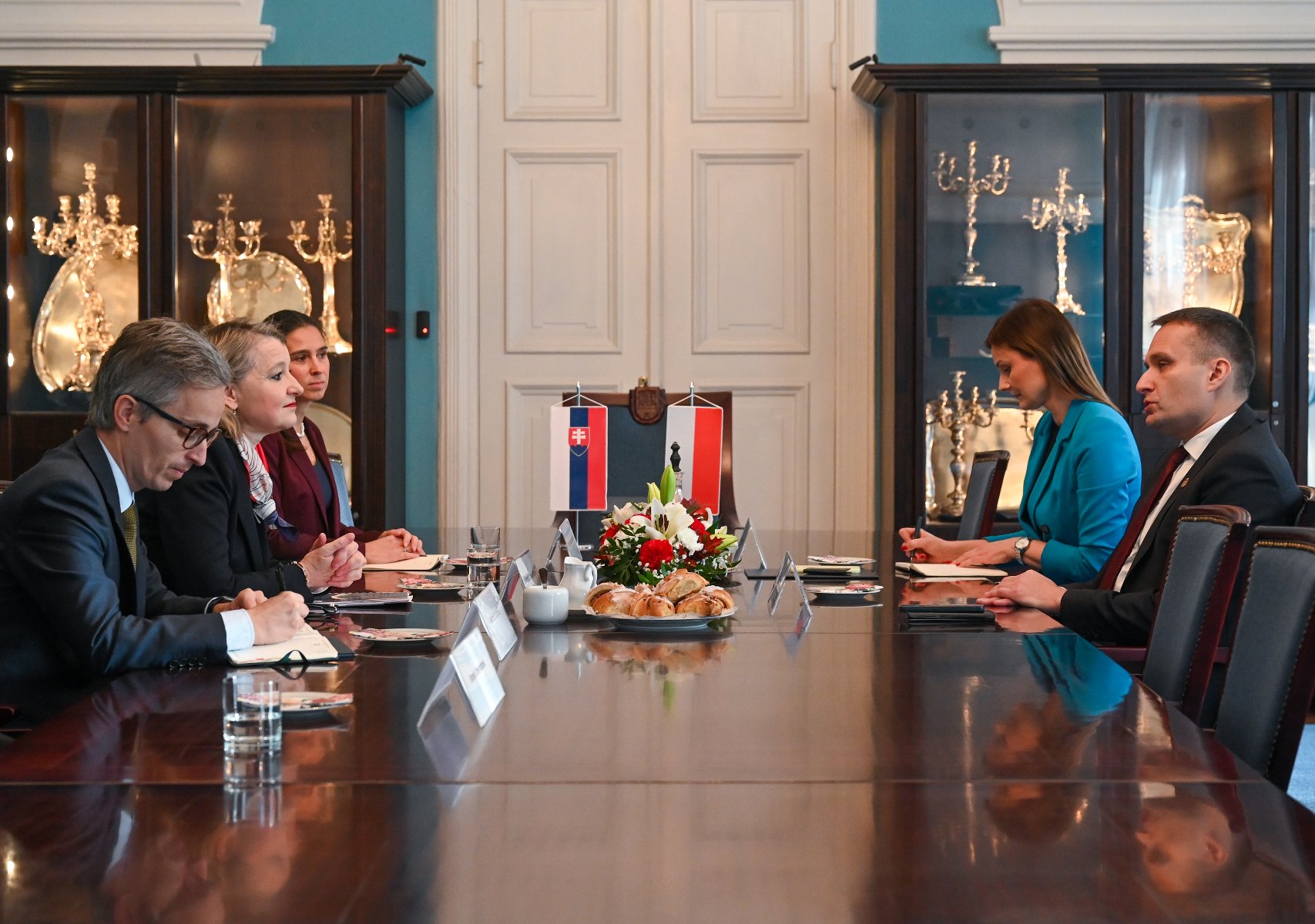 Na zdjęciu reprezentacyjna sala, w niej, przy dużym stoke, siedzi pięć osób, w centrum flagi Polski i Słowacji - grafika artykułu