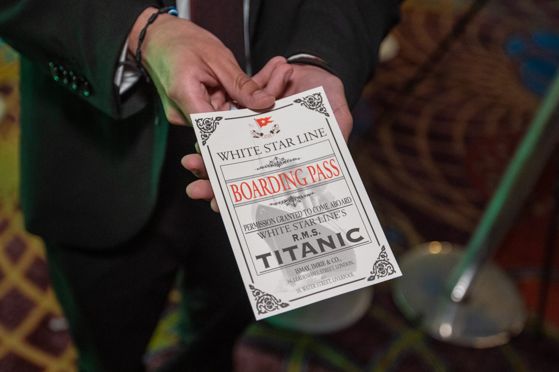 Na zdjeciu mężczyzna podający kartę - bilet na "Titanica", widać tylko jego dłonie - grafika artykułu