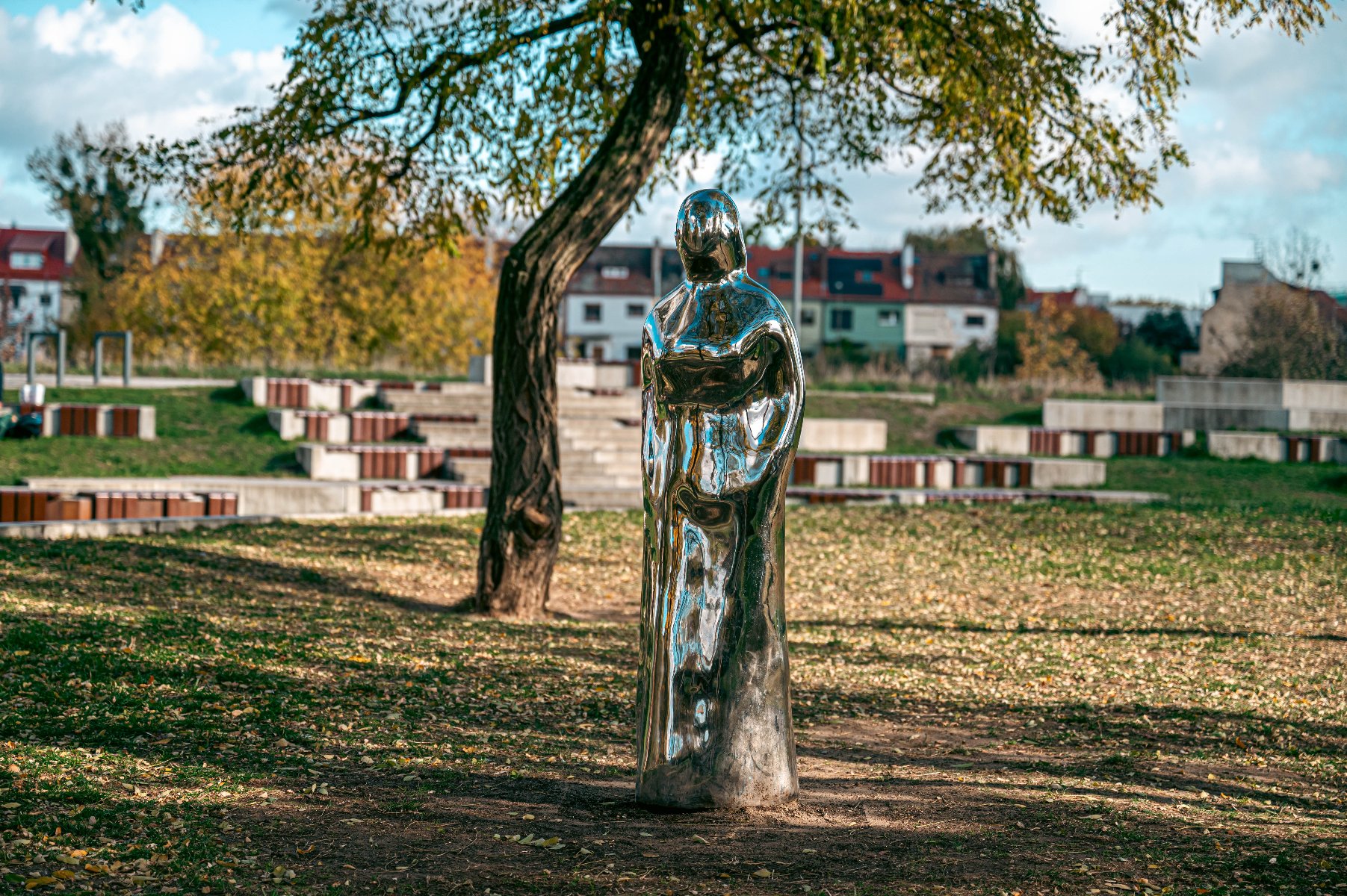 Zdjęcie - Lustrzana bryła kształtem przypominającą sylwetkę kobiety stojąca w parku. - grafika artykułu