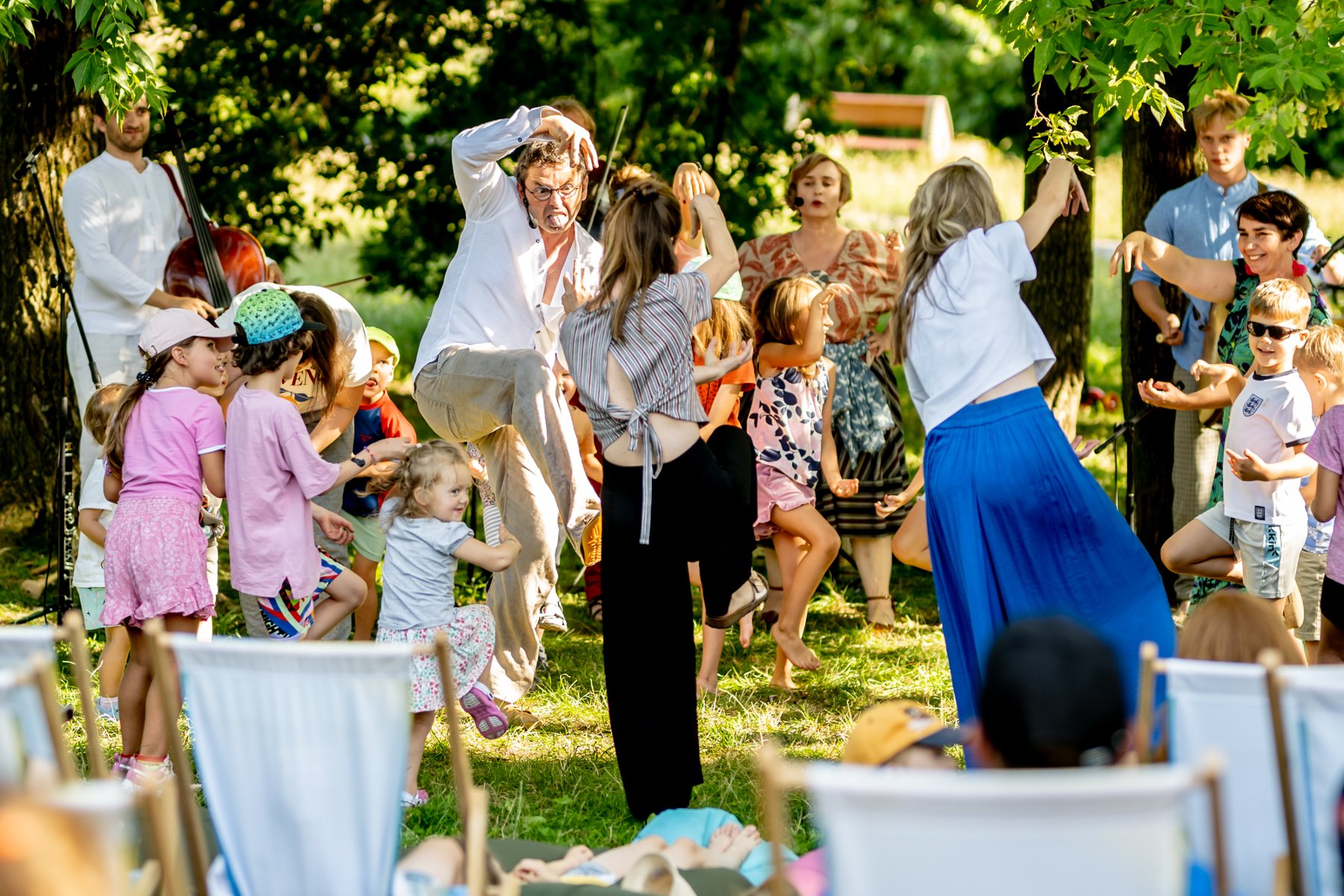 Grupa bawiących się ludzi, dorosłych i dzieci, podczas letniego pikniku w otowczniu drzew. - grafika artykułu