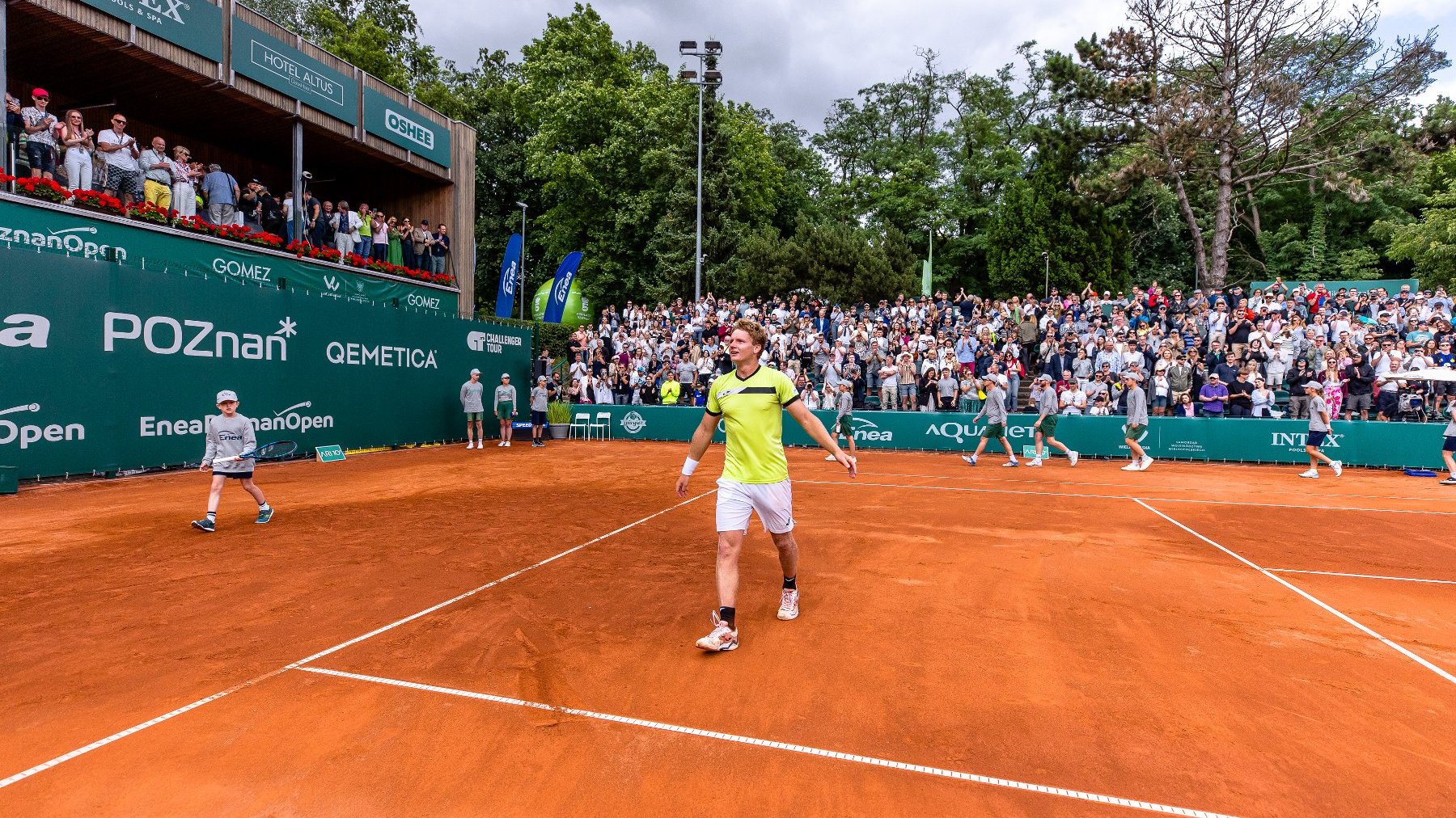 Maks Kaśnikowski wygrywający Enea Poznań Open 2024, fot. Paweł Rychter/Enea Poznań Open - zawodnik w żółtej koszulce i białych spodenkach cieszy się na korcie po zwycięstwie, a w tle widać pełne trybuny oklaskujących go kibiców oraz dzieci do podawania piłek
