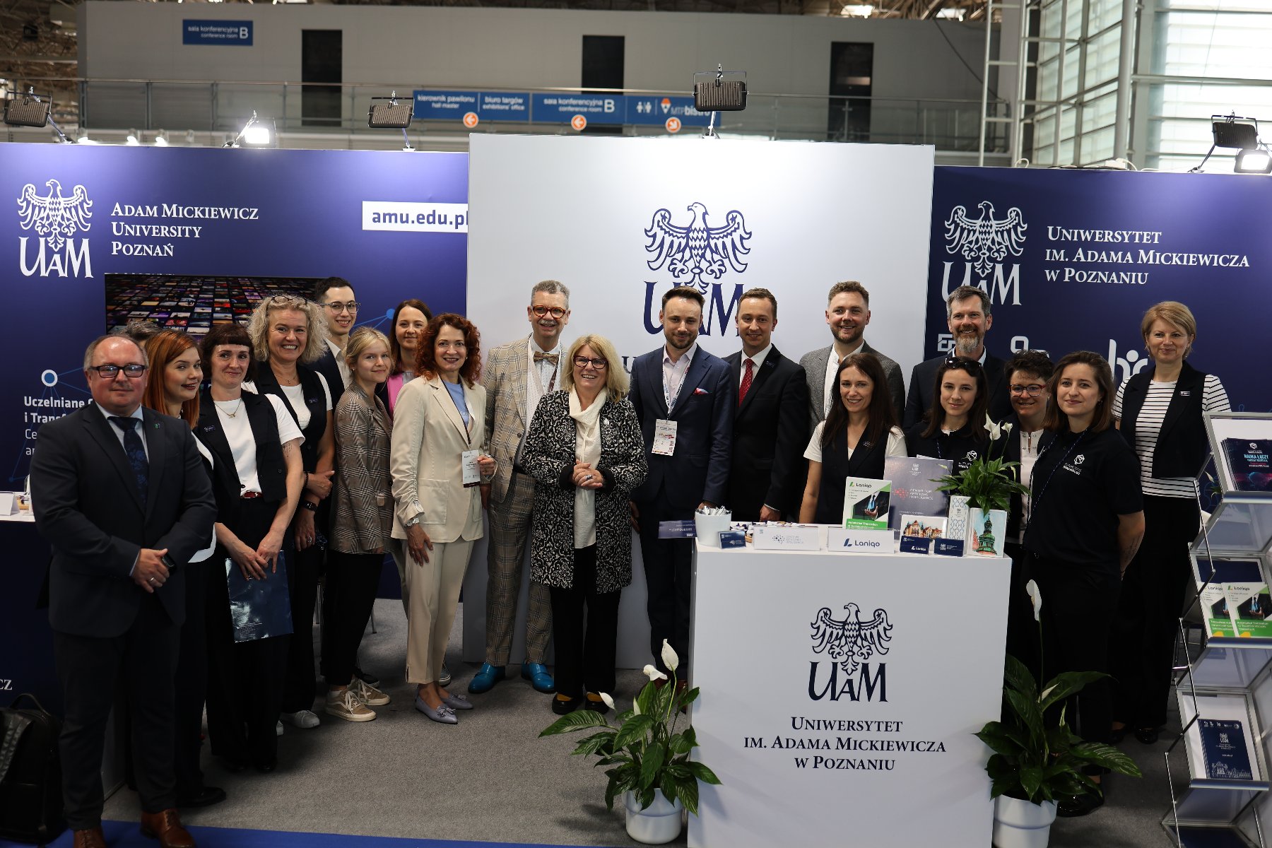 na biało granatowym tle stoi grupa osób pozujących zdjęcia - grafika artykułu