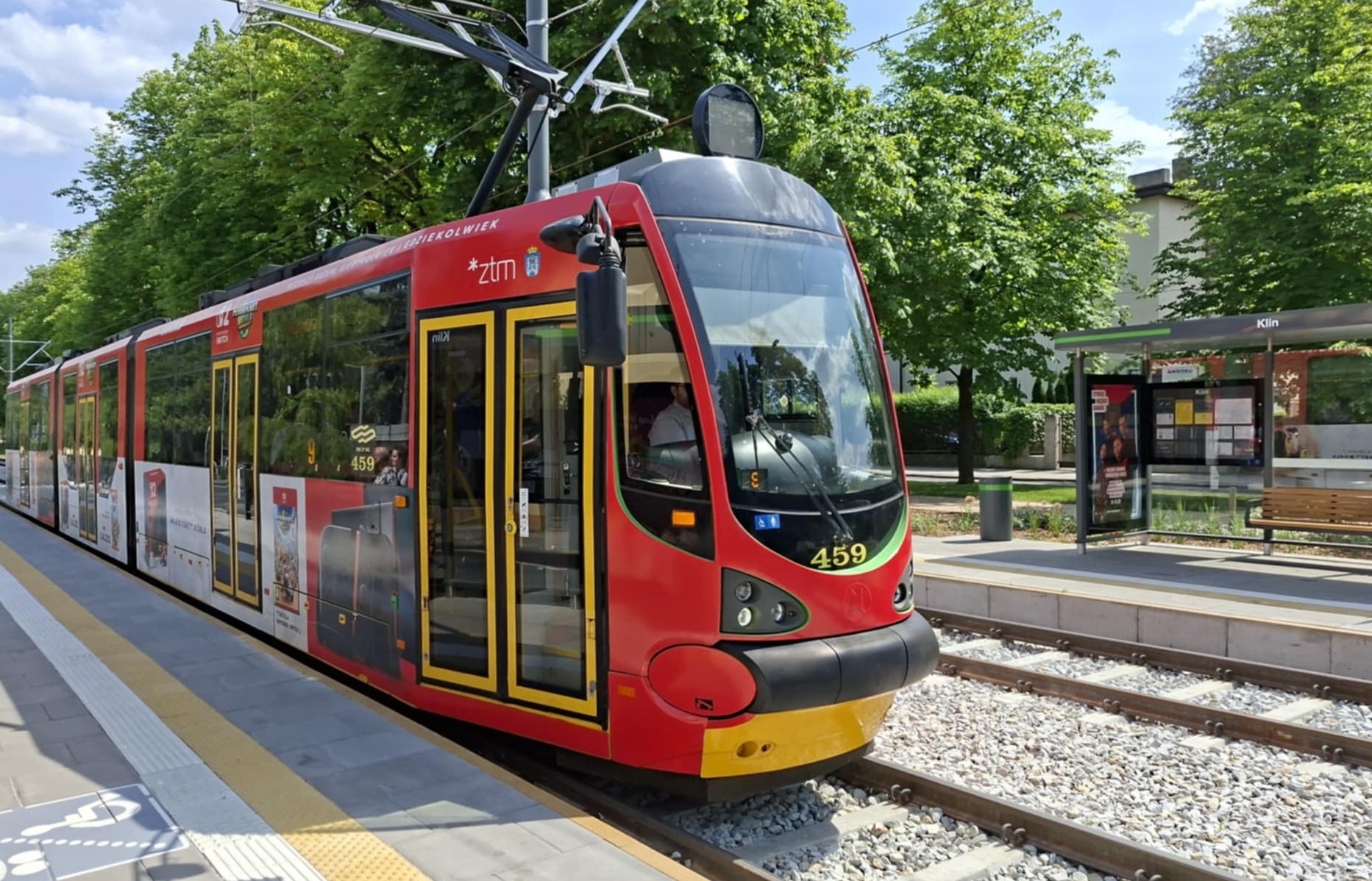 zdjęcie przedstawia czerwony tramwaj, stojący na przystanku - grafika artykułu