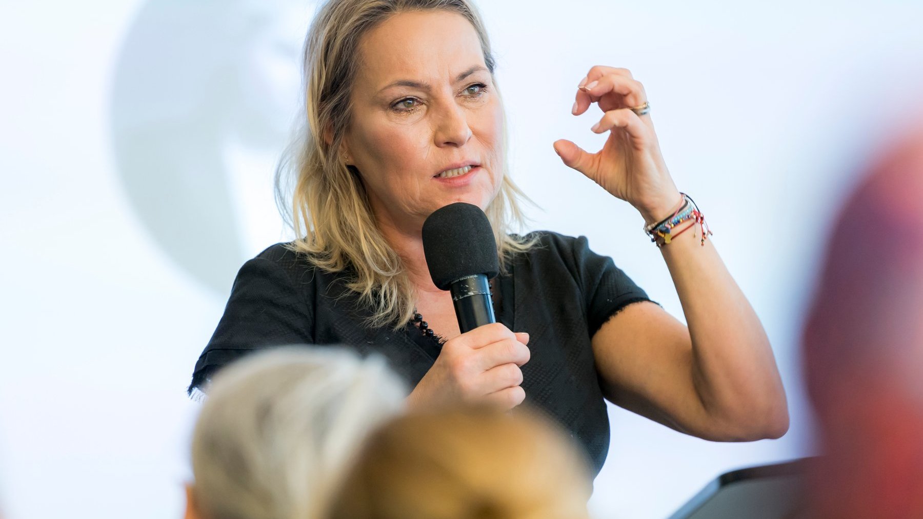 Na zdjęciu gestykulująca kobieta, mówiąca coś do mikrofonu