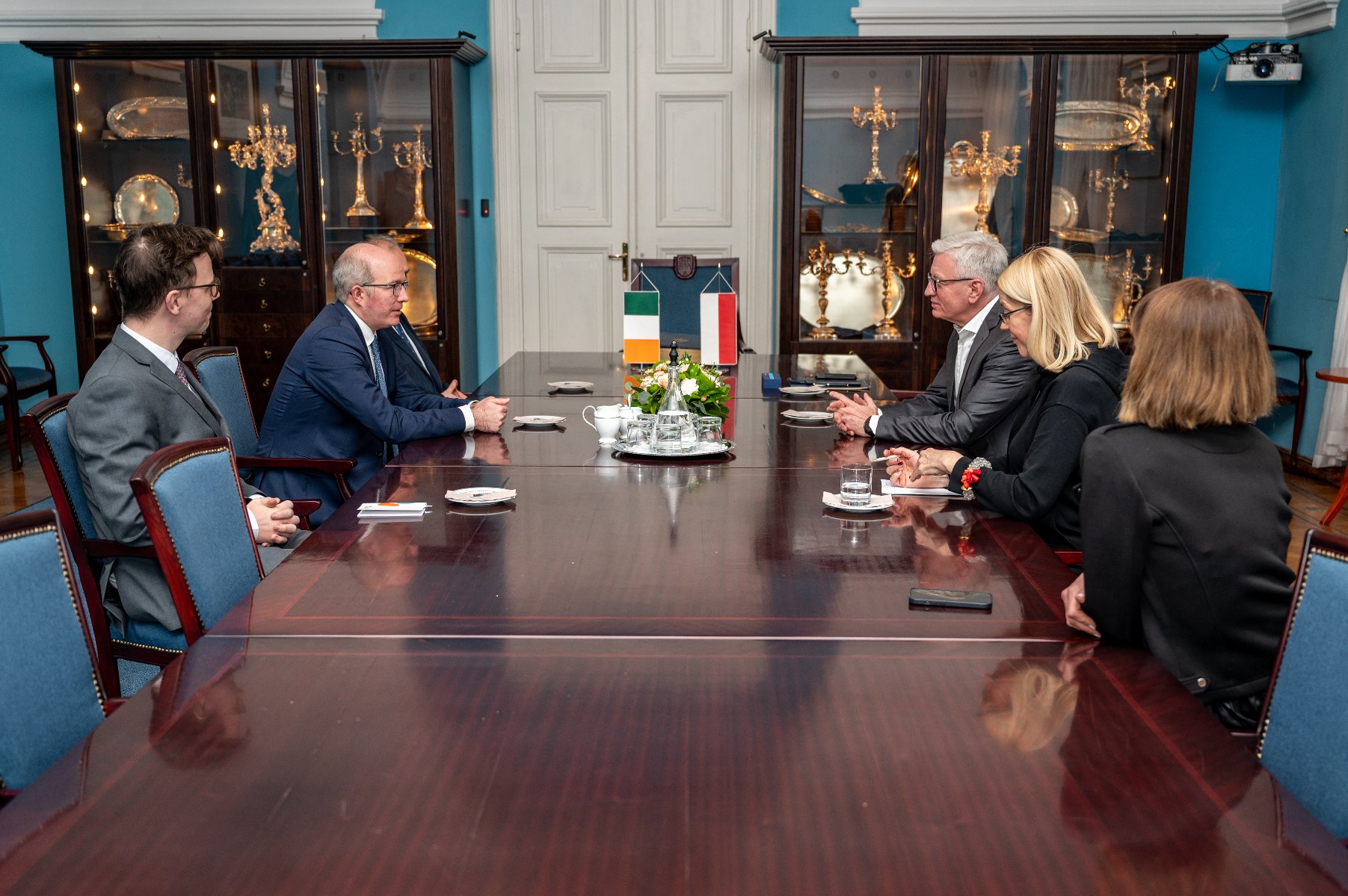 Na zdjęciu widać kilka osób siedzących przy długim stole, wśród nich są m.in. Patrick Haughey, ambasadora Irlandii w Polsce oraz Jacek Jaśkowiak, prezydent Poznania. - grafika artykułu