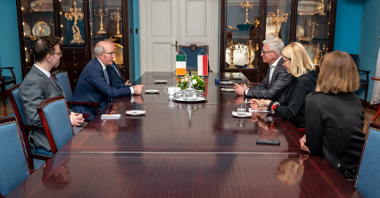 Na zdjęciu widać kilka osób siedzących przy długim stole, wśród nich są m.in. Patrick Haughey, ambasadora Irlandii w Polsce oraz Jacek Jaśkowiak, prezydent Poznania.