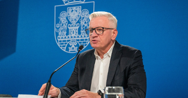 Na zdjęciu prezydent Poznania za stołem konferencyjnym, przy mikrofonie