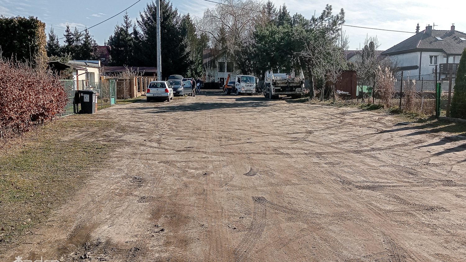 Gruntowa ulica Dziwnowska, po bokach zieleń i zabudowania