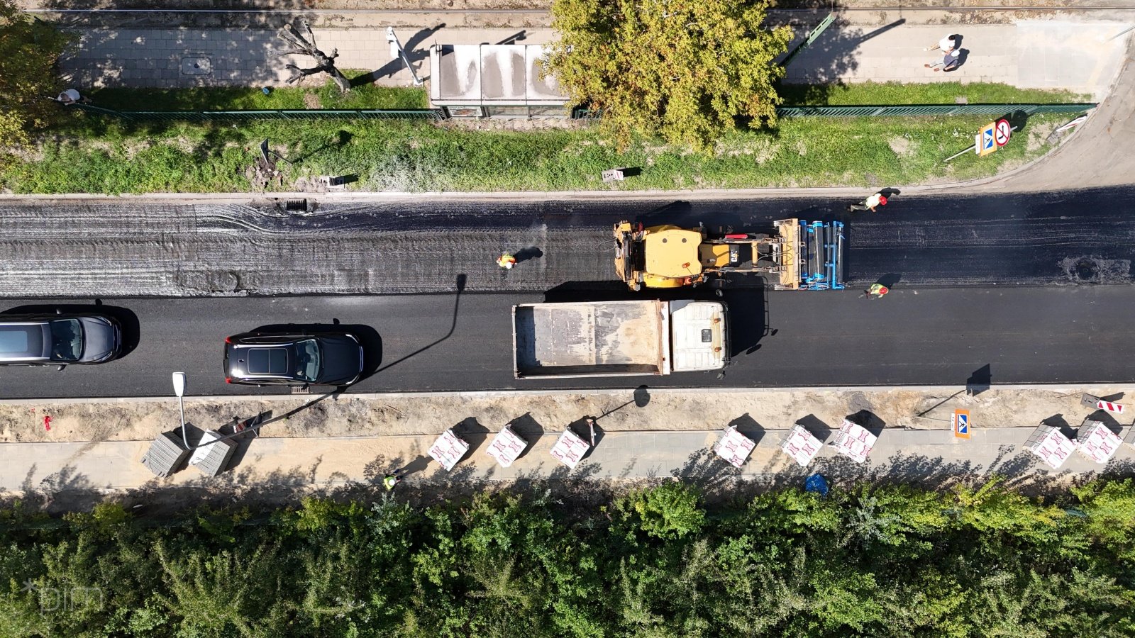 Zdjęcie przedstawia remontowaną jezdnię, z maszynami budowlanymi i robotnikami. Zrobiono je z góry.