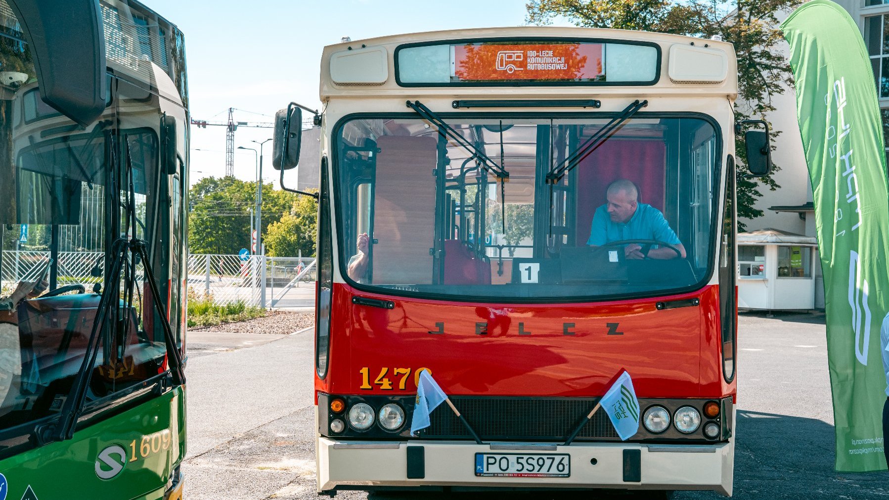 Na zdjęciu stary czerwony autobus, obok stoi nowy, zielony