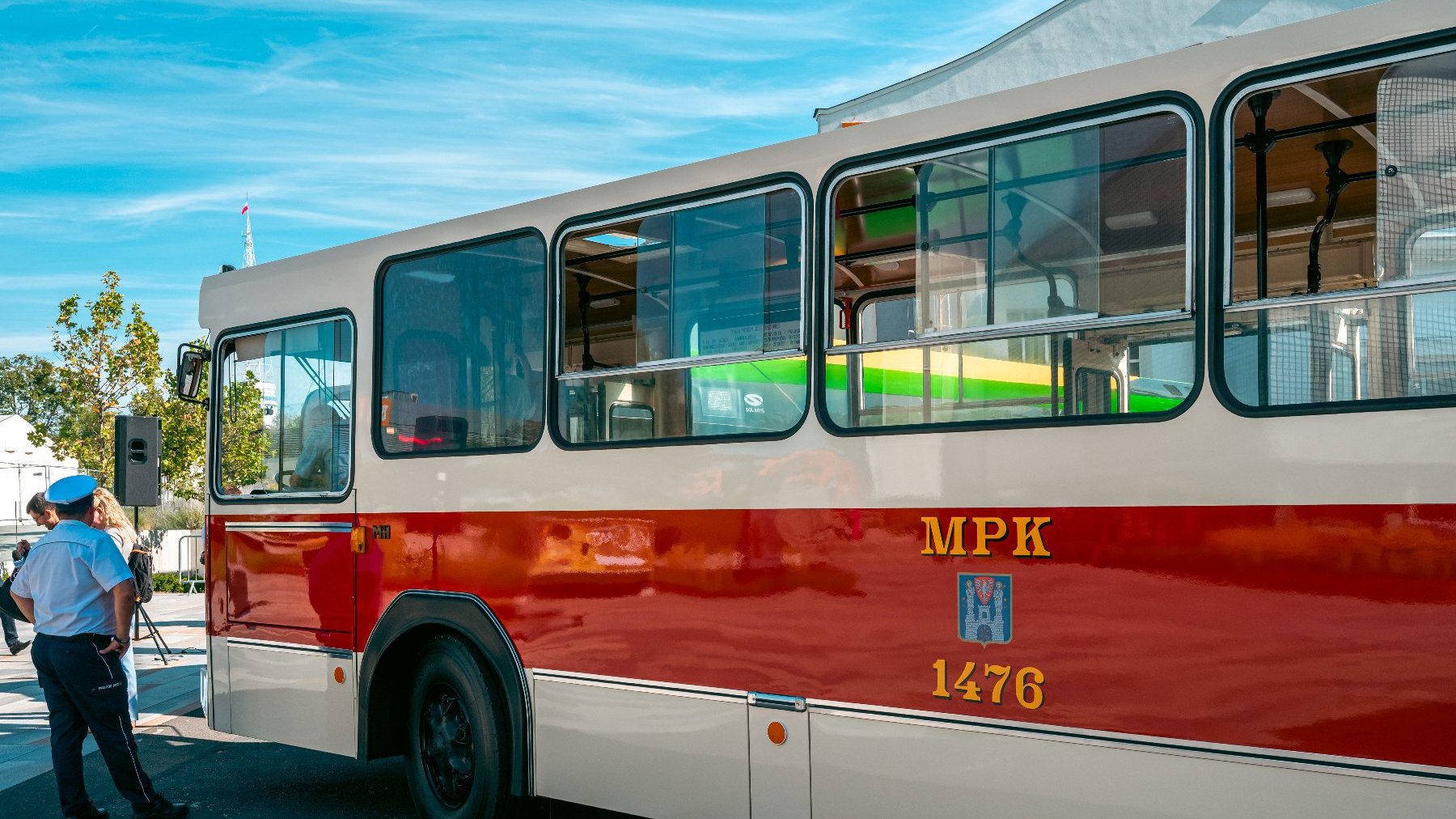 Na zdjęciu zabytkowy autobus, przygląda mu się mężczyzna w czapce