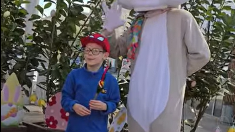 Osoba przebrana za zająca. Obok chłopiec, trzymający w ręce palmę wielkanocną.