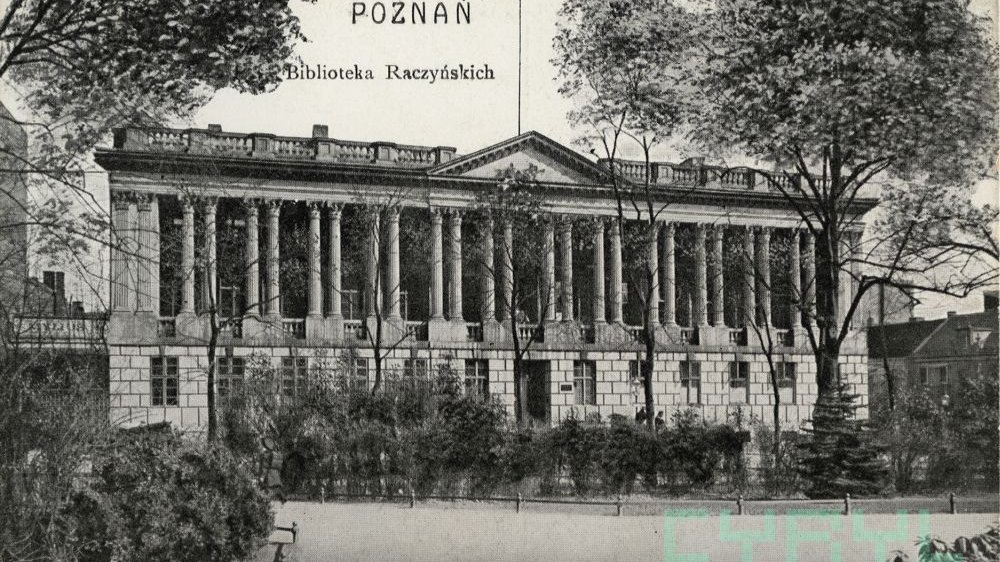 Pocztówka ze zdjęciem budynku biblioteki z charakterystycznymi kolumnami. Dookoła dużo zieleni.