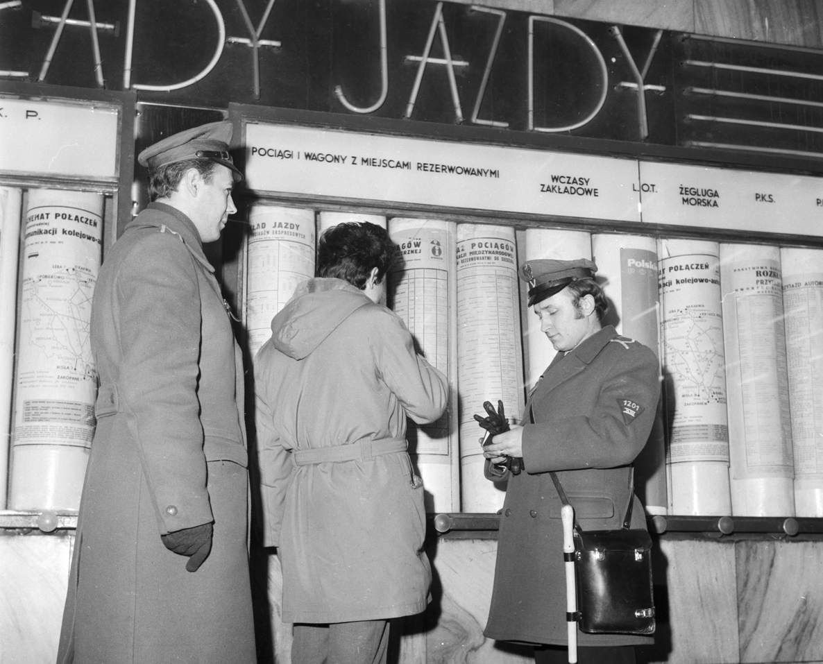 Dwaj milicjanci, w mundurach z lat 70, przeglądają dokumenty mężczyzny - grafika artykułu
