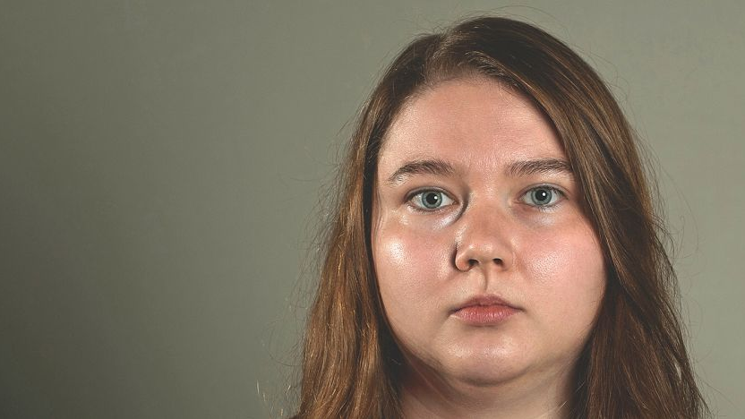Poetka ma długie, rudawe włosy i okrągłą rozświetloną twarz.