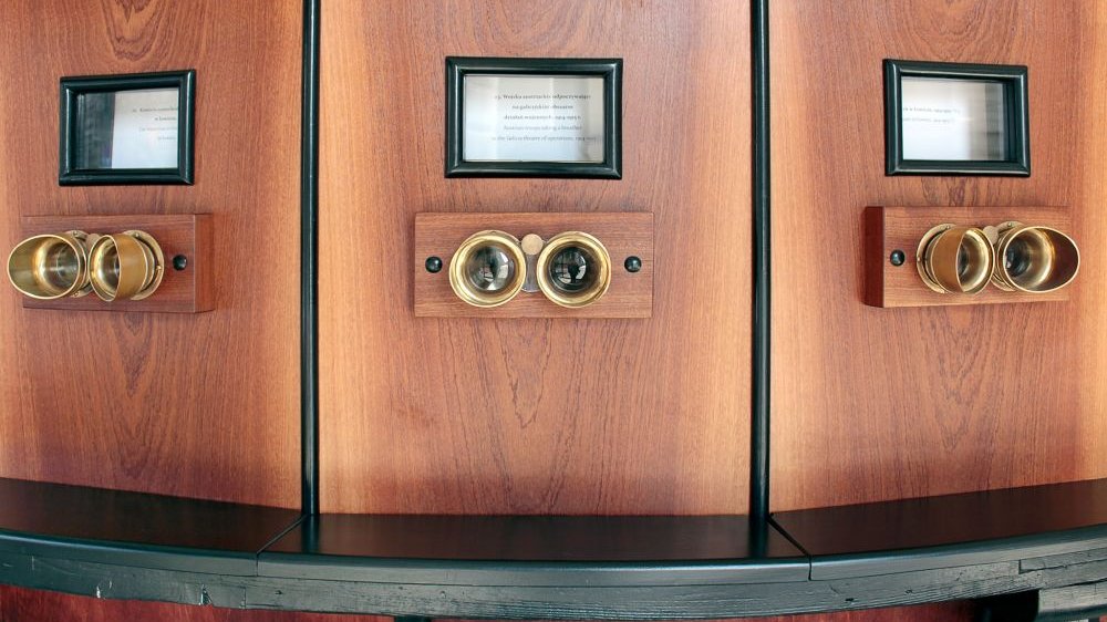 Metalowe wizjery do których przykłada się oczy i okienka z opisem bieżącego w kolejności zdjęcia w drewnianej obudowie Fotoplastykonu.