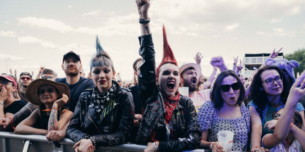 Dwie młode dziewczyny z kolorowymi irokezami na głowach w tłumie pod sceną. - grafika artykułu