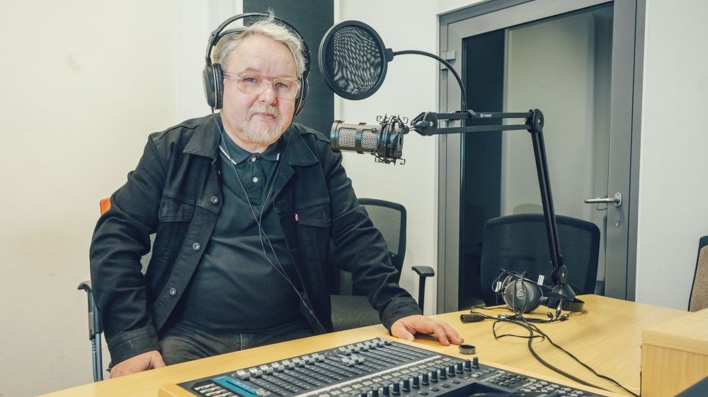Pisarz w słuchawkach, przed radiowym mikrofonem.