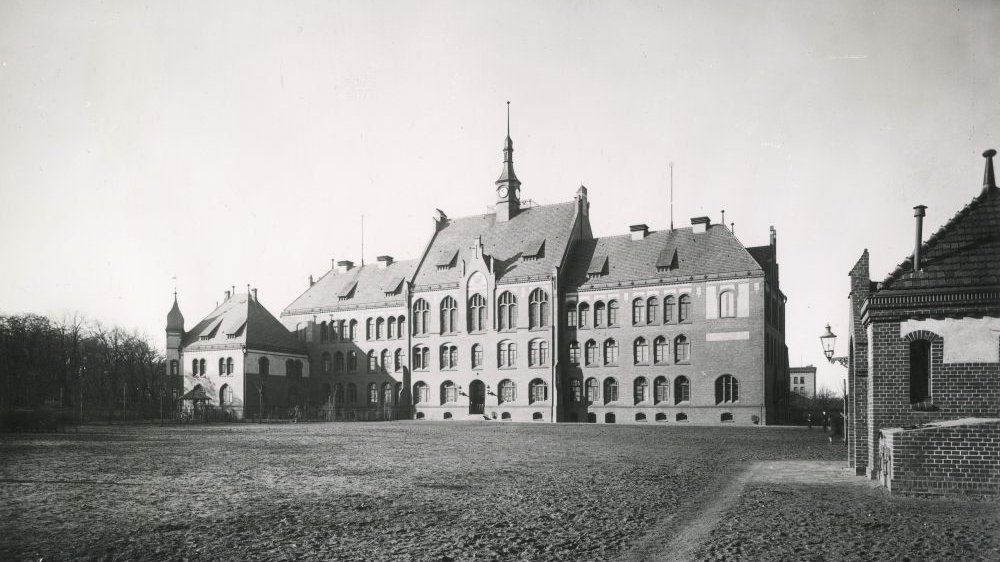 Monumentalny budynek z dużymi oknami i wieżyczką na dachu.