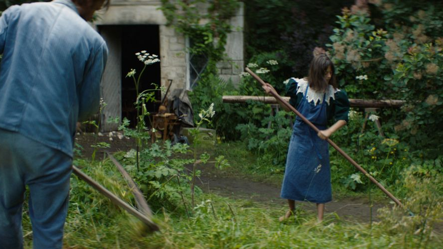 Dziewczyna grabi liście, obok mężczyzna kosi trawę.