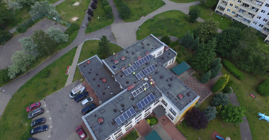 Zdjęcie przedstawia budynek przedszkola widziany z góry. Na dachu widać panele fotowoltaiczne.
