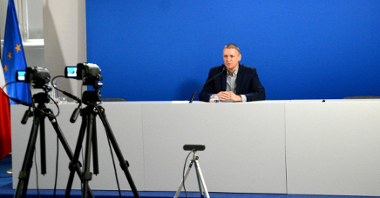 Zdjęcie przedstawia Patryka Pawełczaka, dyrektora Gabinetu Prezydenta UMP. Dyrektor siedzi za biurkiem, na pierwszym planie widać kamery.