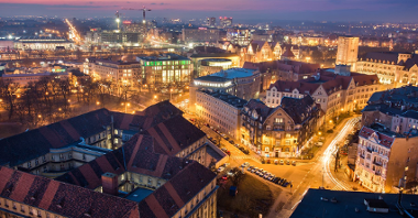 Na zdjęciu panorama Poznania o zmroku, widać dachy kamienic i Okrąglak