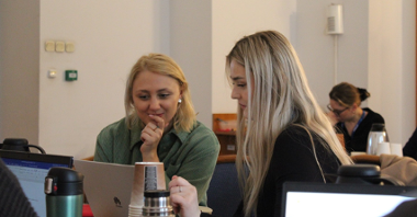 Na obrazku widać dwie młode kobiety patrzące w ekran komputera