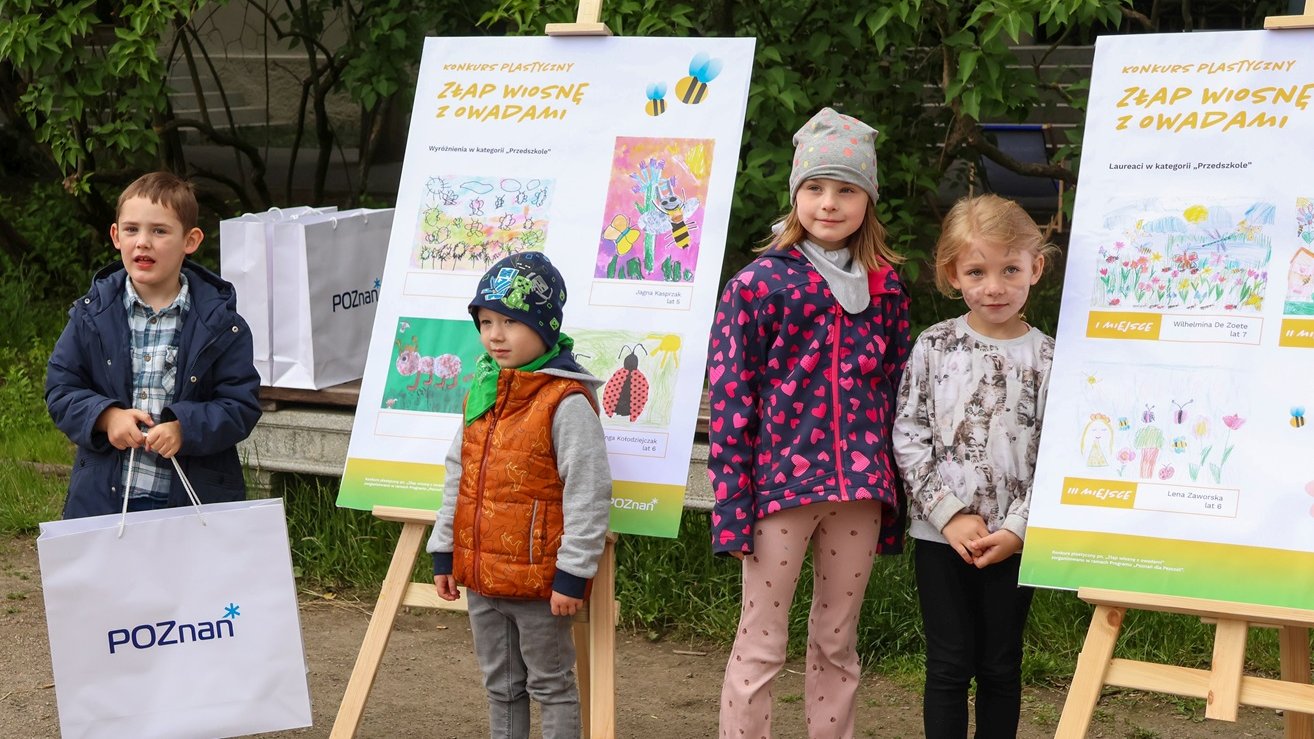 Czwórka dzieci, które zdobyły nagrody w konkursie plastycznym na tle swoich prac.