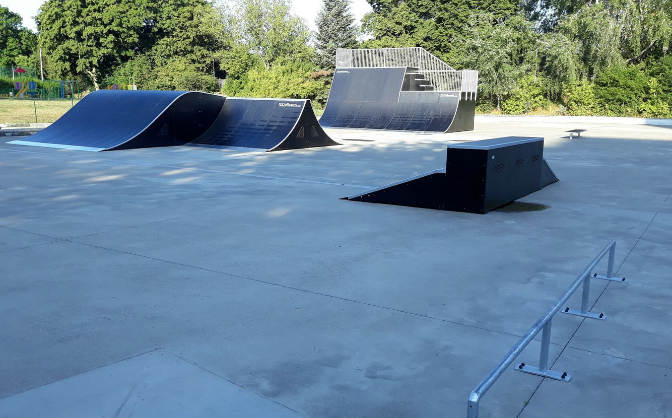 oddkryty skatepark z obiektami do uprawiania tych dyscyplun sportu, wokół obiketu drzewa i krzewy