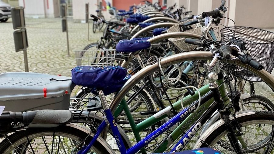 Zdjęcie z parkingu pełnego rowerów mających granatowe osłobki na krzesełko z logo smart city Poznań.