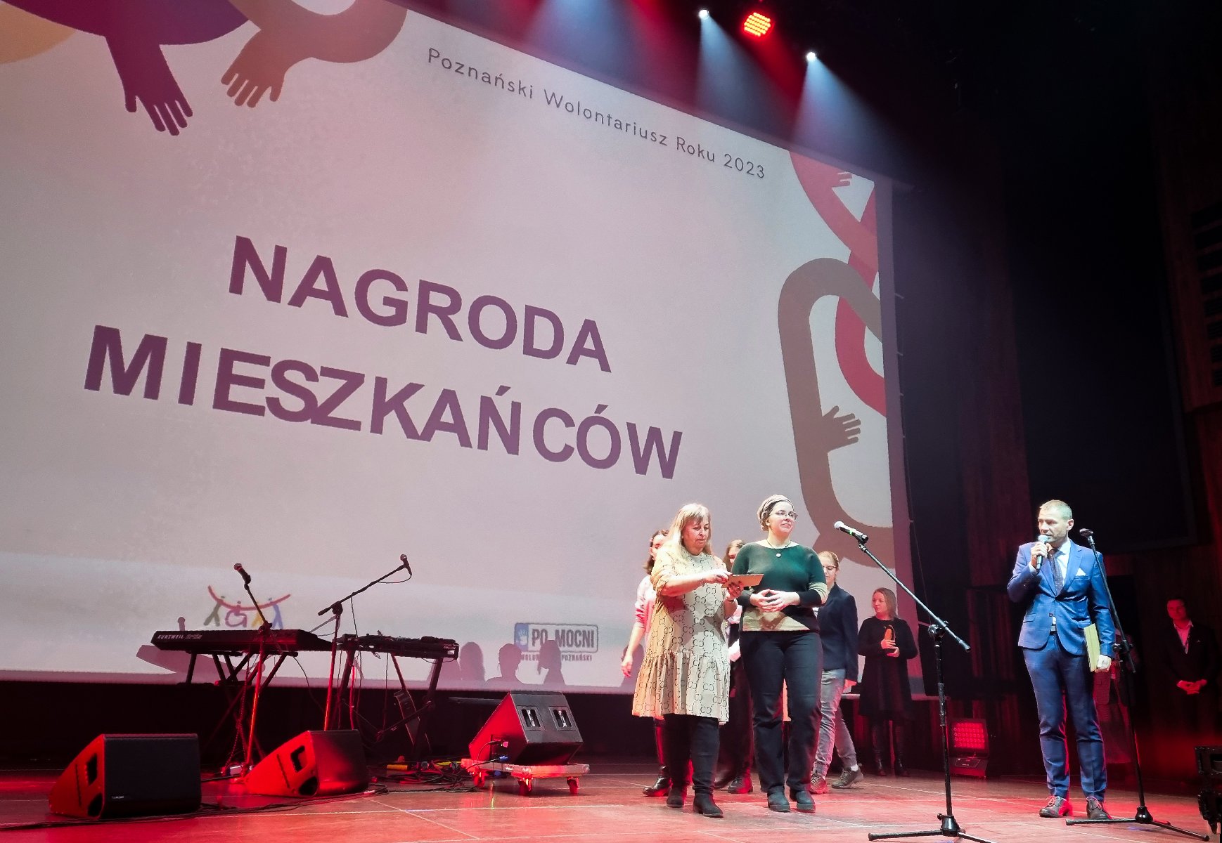 scena, ludzie przy mikrofonie, w tle na ekranie widoczny napis NAGRODA MIESZKAŃCÓW