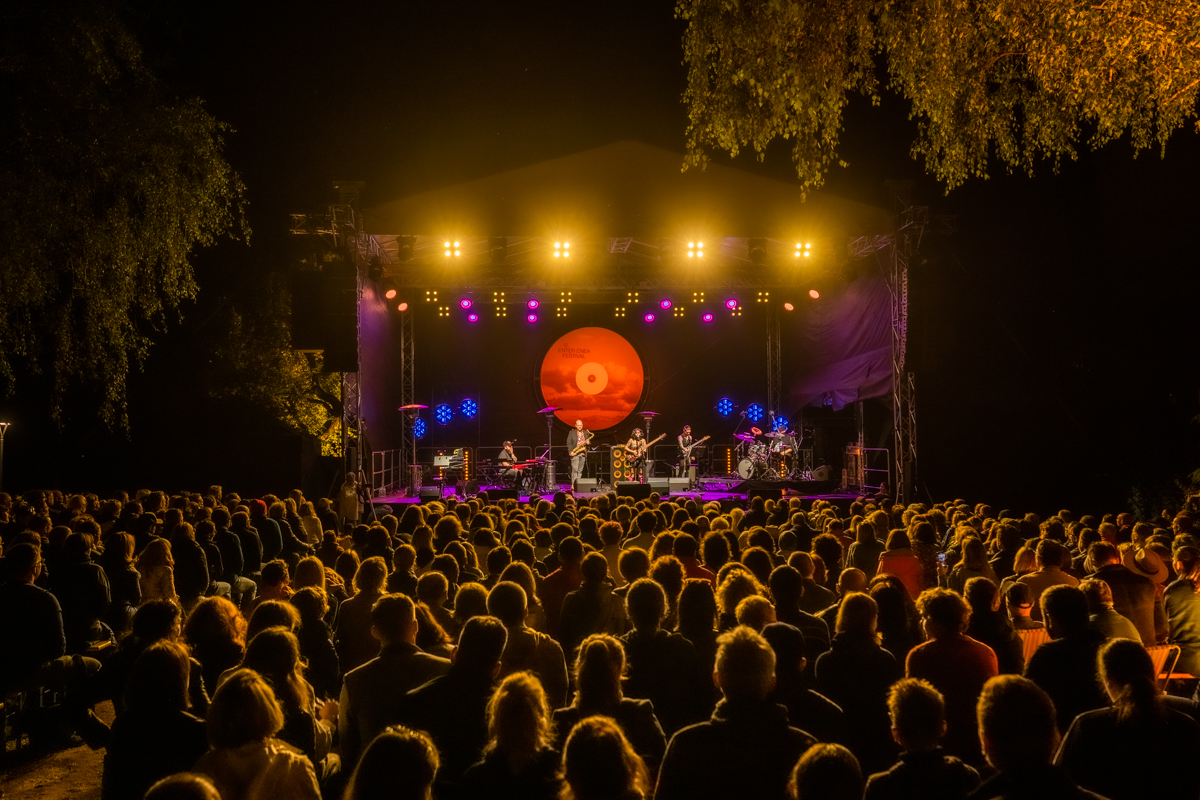 Scena w półmroku, na niej muzycy, przed sceną tłum zasłuchanej publiczności.