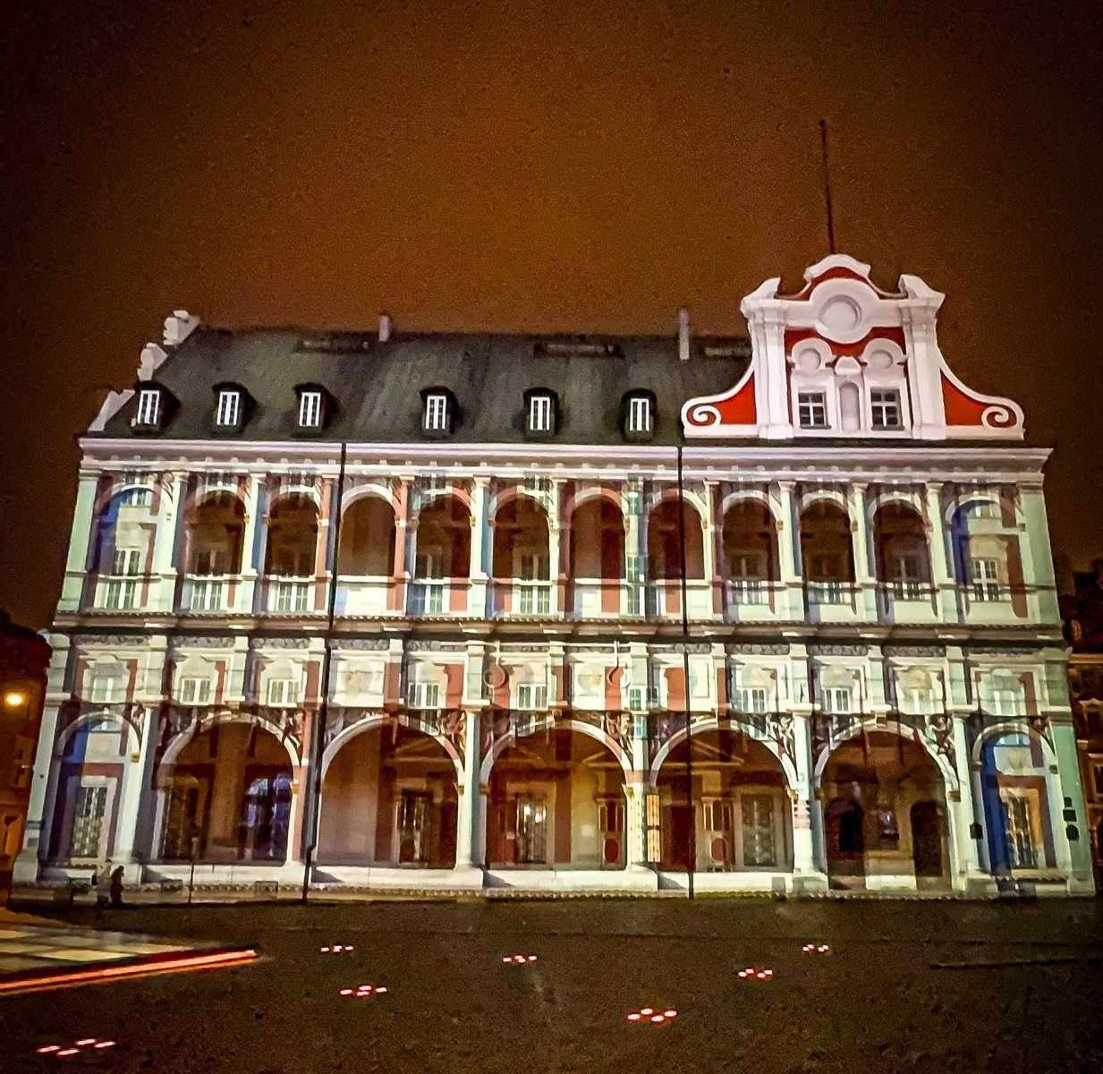 Zdjęcie przedstawia budynek Urzędu Miasta Poznania, po zmroku z mapingiem świetlnym.